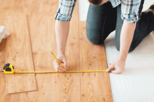 Close up of male hands measuring wood flooring