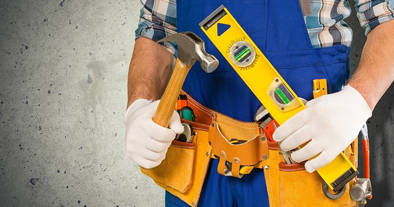 a person holding remodeling tools like a hammer and a level.