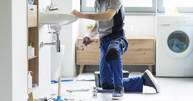 a person working on a sink in the laundry room