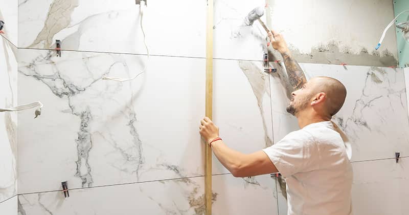 a person working on tile in a bathroom remodeling job