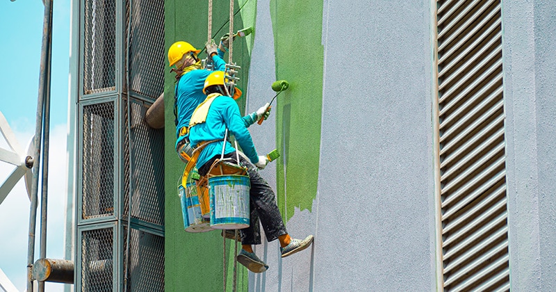 two painters working on a painting job and painting the exterior of a building