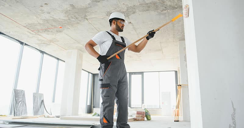 a person painting the interior wall with a roller