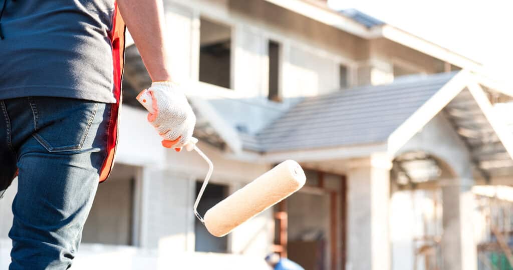painting contractor standing in front of house with a roller