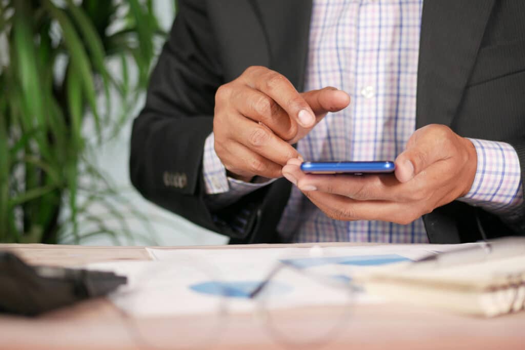 Person using a mobile device to access field service management software for scheduling and job updates.