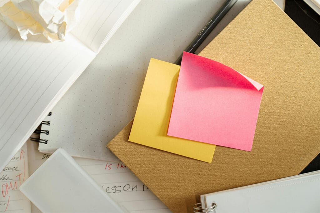 Sticky notes and scattered notebooks representing disorganized scheduling before field service software.