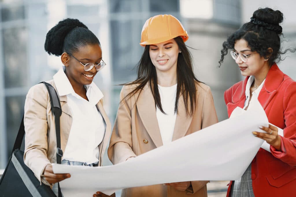 Three construction team members reviewing project plans together during project coordination on-site.