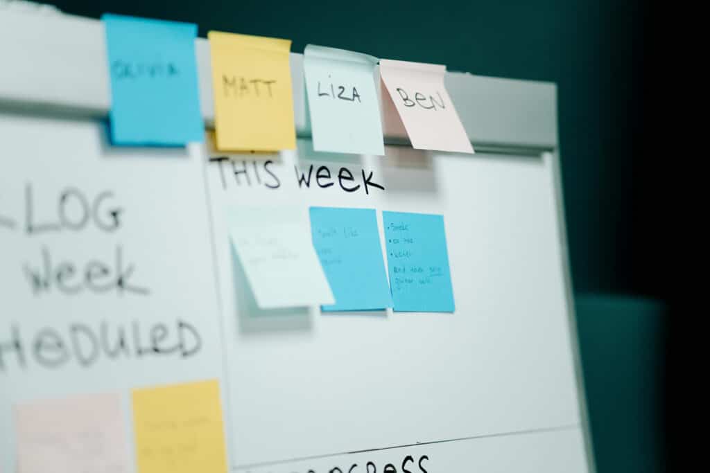 Whiteboard with color sticky notes showing team tasks and weekly planning for small business workflow.