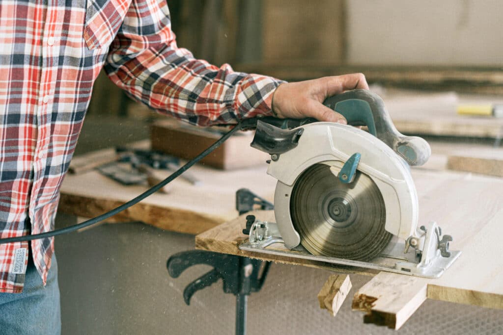Contractor cutting wood with a circular saw during hands-on work experience for a home improvement license.