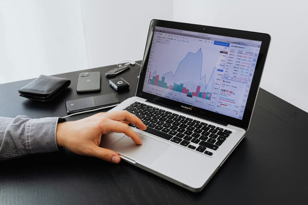 A small business owner reviews charts on a laptop, displaying business data and software dashboards.