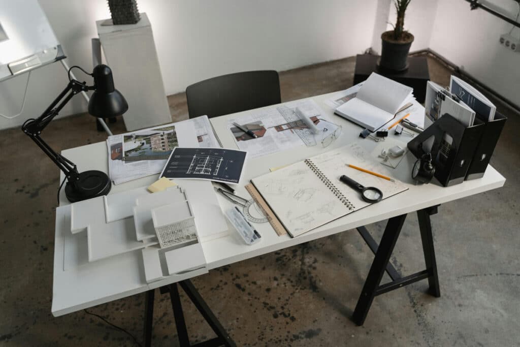 Construction project desk filled with blueprints, sketches, tools, and documents for project planning.